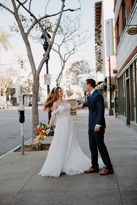  bride in a full skirt gown with an off the shoulder detail and the groom in dark blue suit and bow tie 