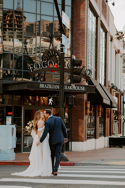  bride in a full skirt gown with an off the shoulder detail and the groom in dark blue suit and bow tie 