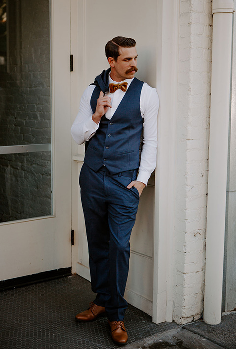  bride in a full skirt gown with an off the shoulder detail and the groom in dark blue suit and bow tie