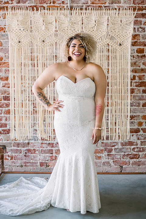  the bride is in a white formfitting lace gown with a sweetheart neckline and fun velvet shoes