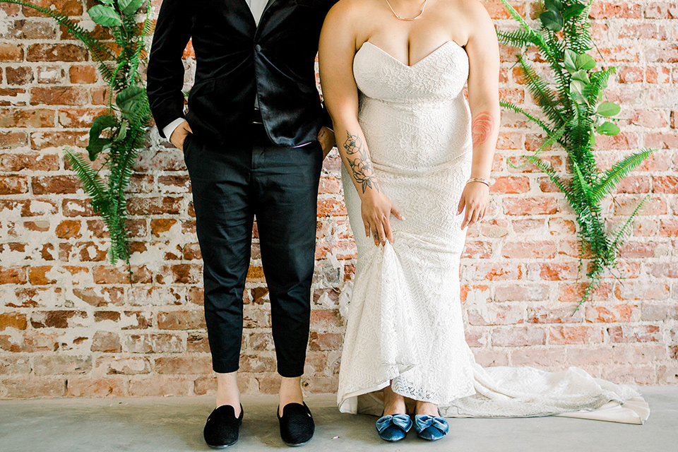  the bride is in a white formfitting lace gown with a sweetheart neckline and fun velvet shoes and the groom in a black velvet tuxedo with a cropped pant and bow tie exchanging rings