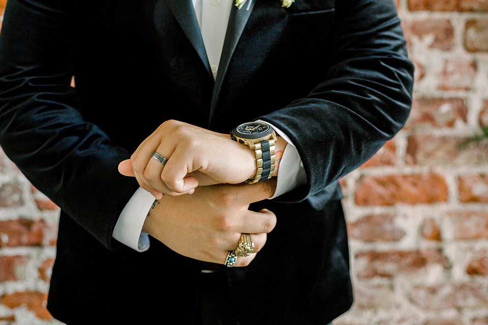  the groom in a black velvet tuxedo with a cropped pant and bow tie exchanging rings