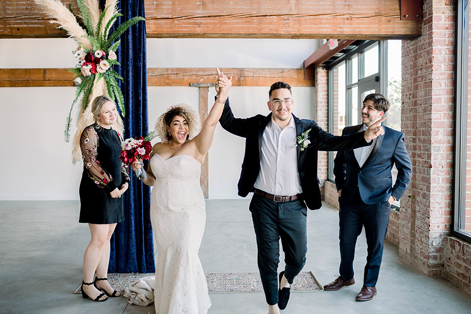  the groom in a black velvet tuxedo with a cropped pant and bow tie exchanging rings