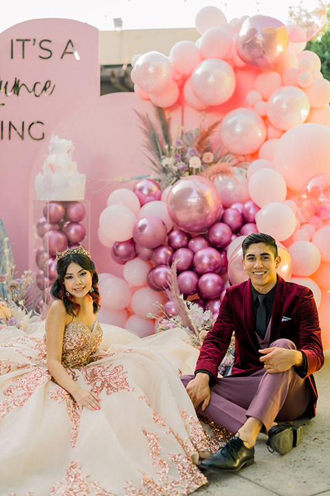  chambelanes style with a burgundy velvet tuxedo, rose pink pants and vest, and a black shirt and the birthday girl in a gold and pink gown with a strapless neckline and lace detailing 
