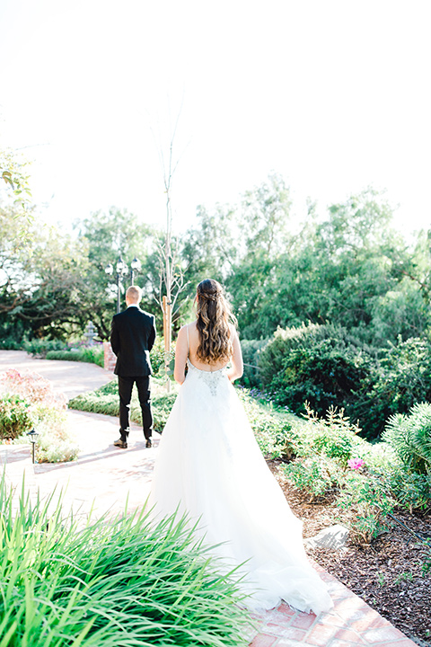  bride in a fit and flare gown with a strapless neckline and lace, the groom in a black tuxedo with a black bow tie first look