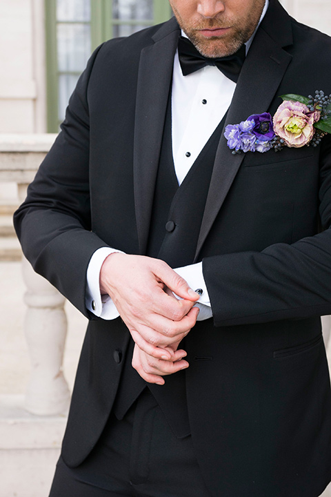  groom in a black tuxedo and a black bow tie with a purple pocket square 