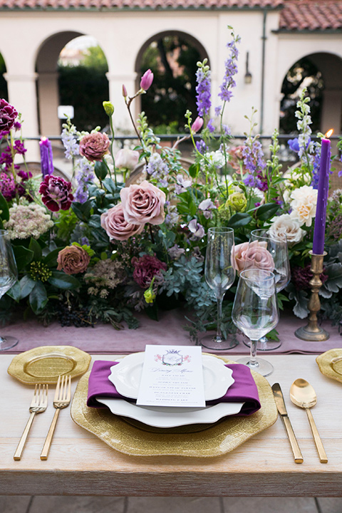  white plates with royal purple linens and gold flatware