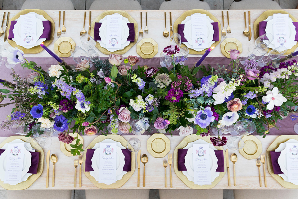  wooden table with white plates and purple linens with purple and green florals