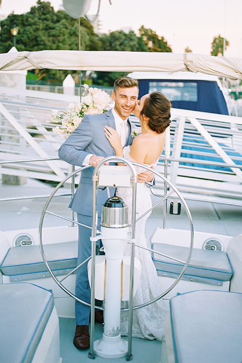  bride in a form fitting gown with an off the shoulder detail and the groom in a light blue suit on a boat