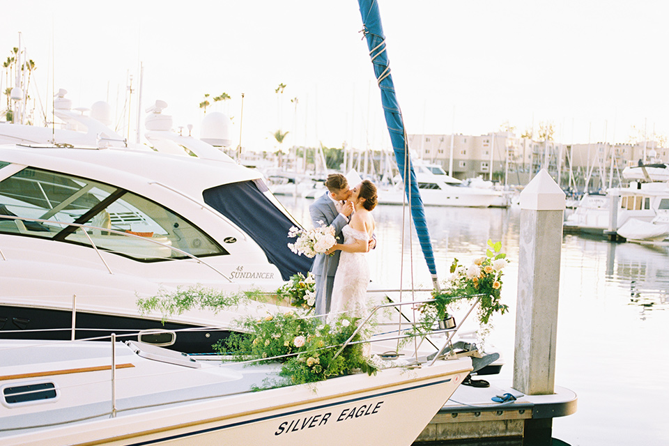  bride in a form fitting gown with an off the shoulder detail and the groom in a light blue suit on the vespa 