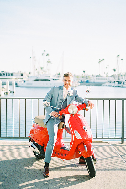  the groom in a light blue suit on a vespa 