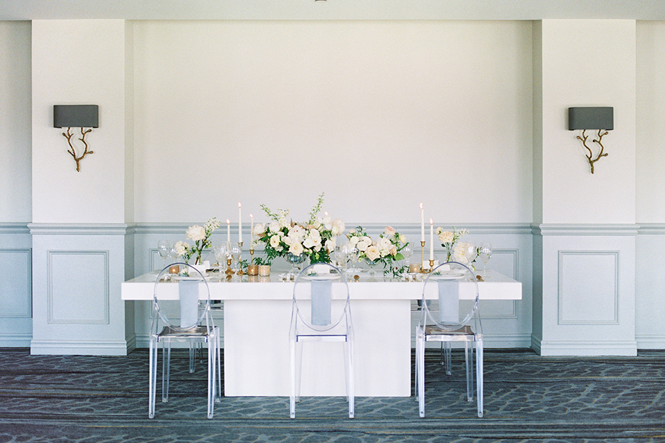  white tablescape with white chairs on it 