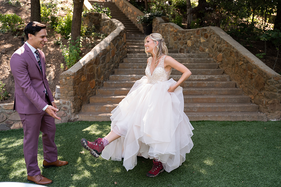  bride in a white ballgown with a deep-v neckline and crystal embellishments and the groom in a rose pink suit with a navy floral neck tie 