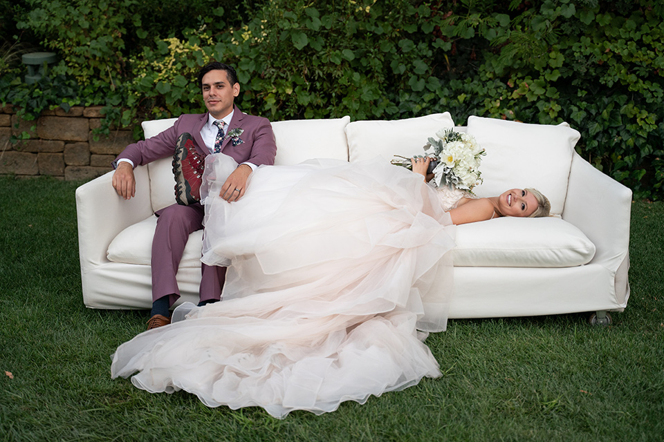  bride in a white ballgown with a deep-v neckline and crystal embellishments and the groom in a rose pink suit with a navy floral neck tie 