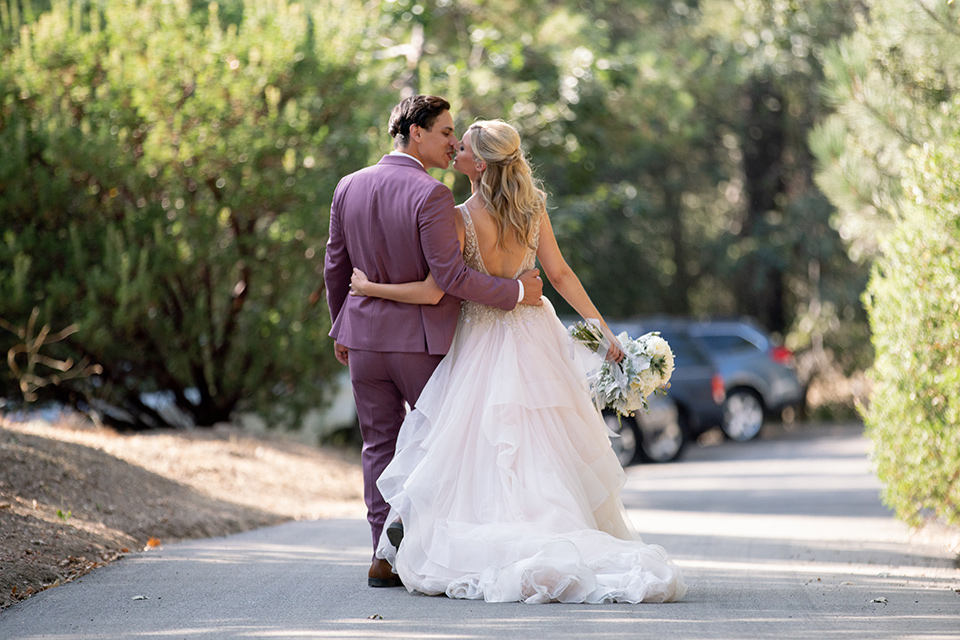  bride in a white ballgown with a deep-v neckline and crystal embellishments and the groom in a rose pink suit with a navy floral neck tie 