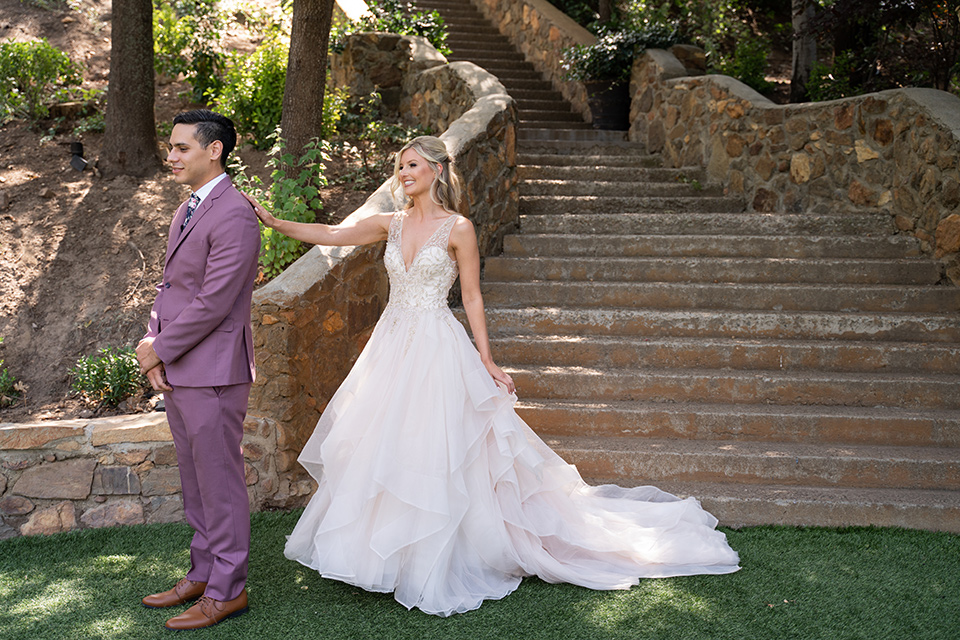  bride in a white ballgown with a deep-v neckline and crystal embellishments and the groom in a rose pink suit with a navy floral neck tie 