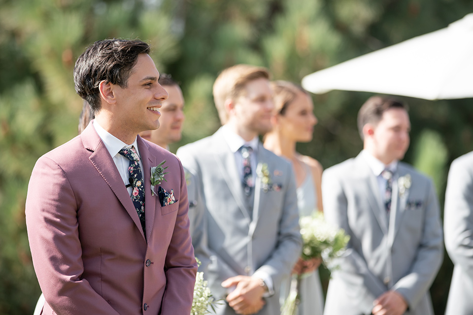  bride in a white ballgown with a deep-v neckline and crystal embellishments and the groom in a rose pink suit with a navy floral neck tie 