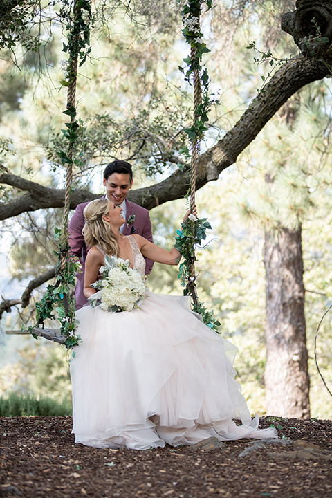 bride in a white ballgown with a deep-v neckline and crystal embellishments and the groom in a rose pink suit with a navy floral neck tie 