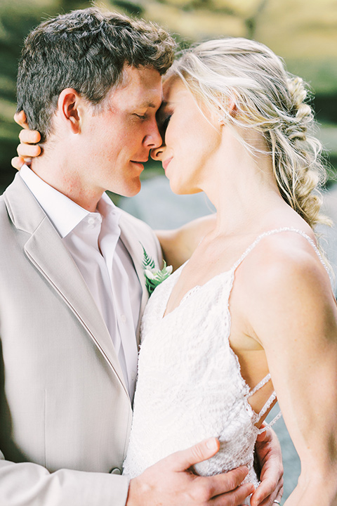  bride in a flowing blush and white gown with a silk style top and the groom in a tan suit with no tie and light brown shoes 