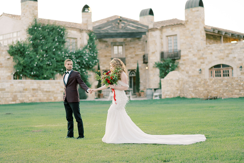  bride in a lace formfitting gown with an off the shoulder detail and the groom in a burgundy tux and black bow tie 