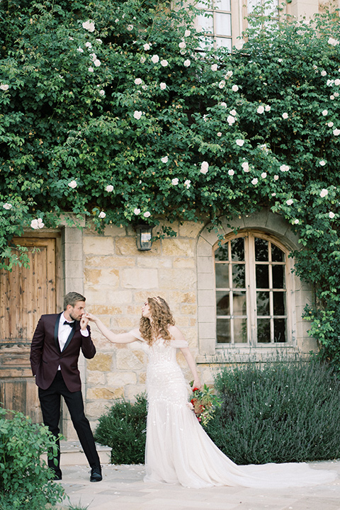  bride in a lace formfitting gown with an off the shoulder detail and the groom in a burgundy tux and black bow tie
