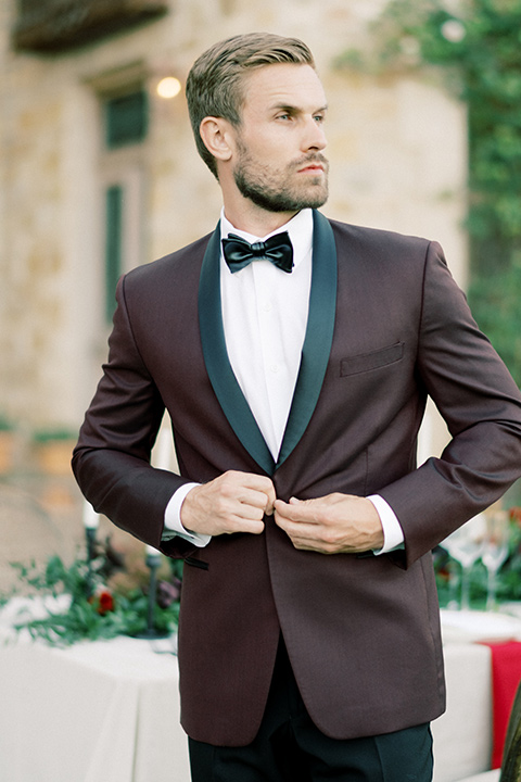  bride in a lace formfitting gown with an off the shoulder detail and the groom in a burgundy tux and black bow tie