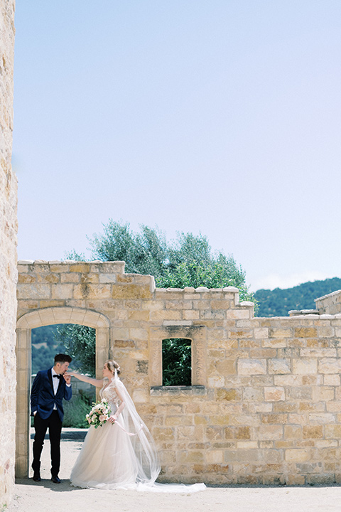 bride in a white long ball gown with tulle train and long cathedral veil and the groom in a blue velvet tuxedo