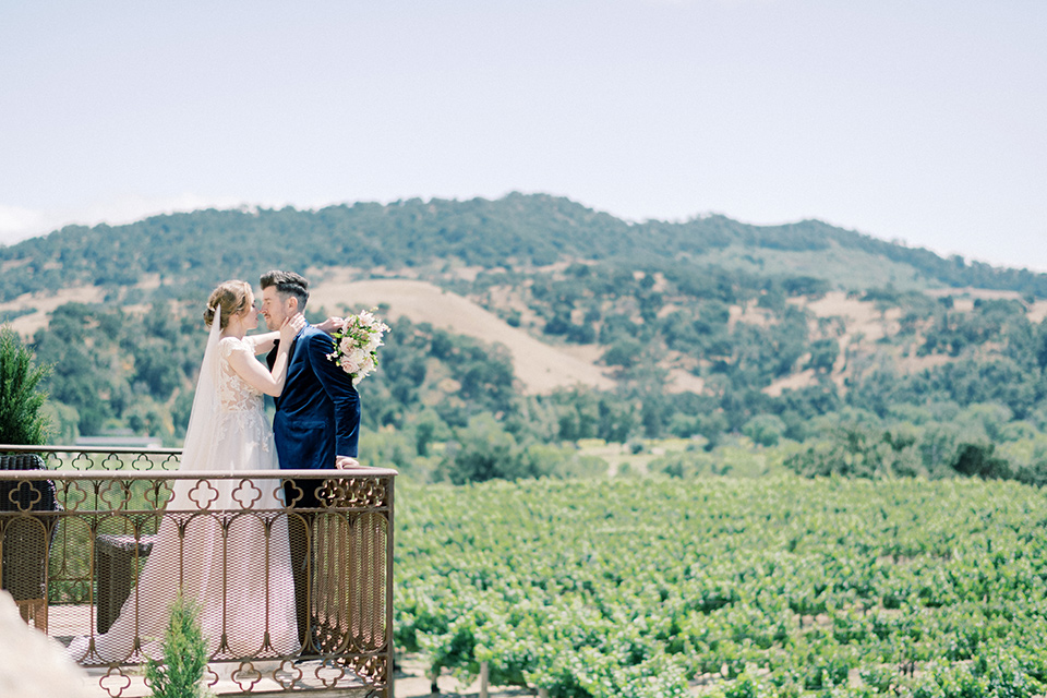  bride in a white long ball gown with tulle train and long cathedral veil and the groom in a blue velvet tuxedo with a black bow tie 