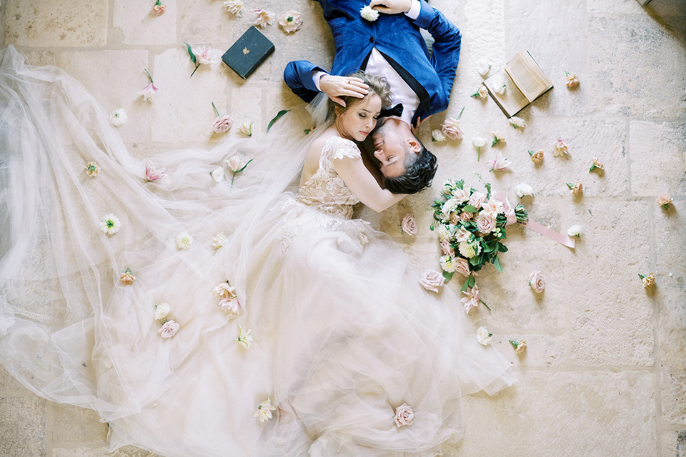  bride in a white long ball gown with tulle train and long cathedral veil and the groom in a blue velvet tuxedo with a black bow tie 