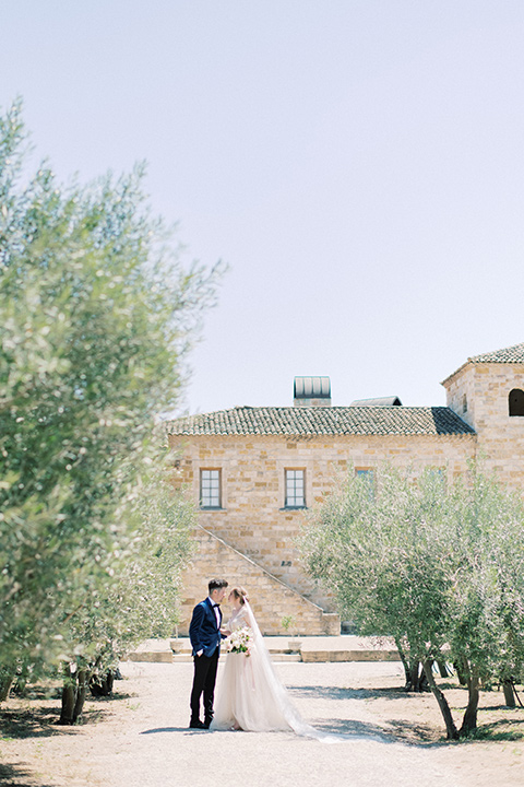  bride in a white long ball gown with tulle train and long cathedral veil and the groom in a blue velvet tuxedo with a black bow tie