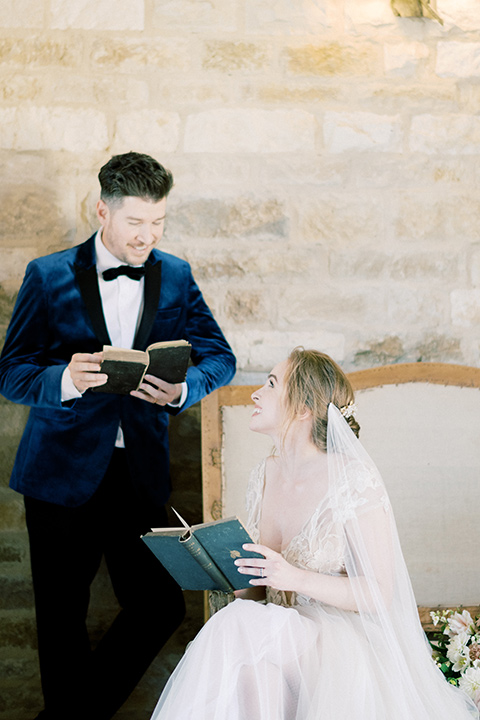 bride in a white long ball gown with tulle train and long cathedral veil and the groom in a blue velvet tuxedo