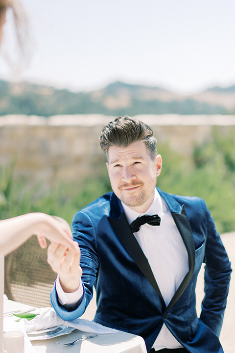  bride in a white long ball gown with tulle train and long cathedral veil and the groom in a blue velvet tuxedo with a black bow tie