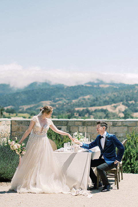 bride in a white long ball gown with tulle train and long cathedral veil and the groom in a blue velvet tuxedo