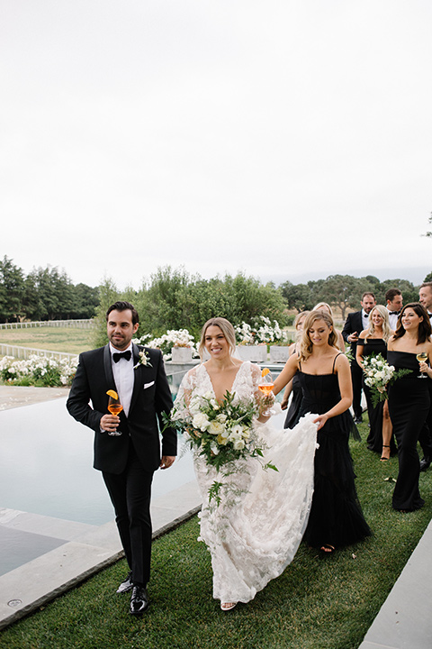  bride in a white gown with floral appliques and trumpet sleeves, the bridesmaids in black dresses in all different styles 