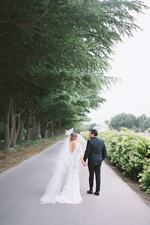  bride in a white gown with floral appliques and trumpet sleeves, the groom in a black tuxedo with black tie accessories