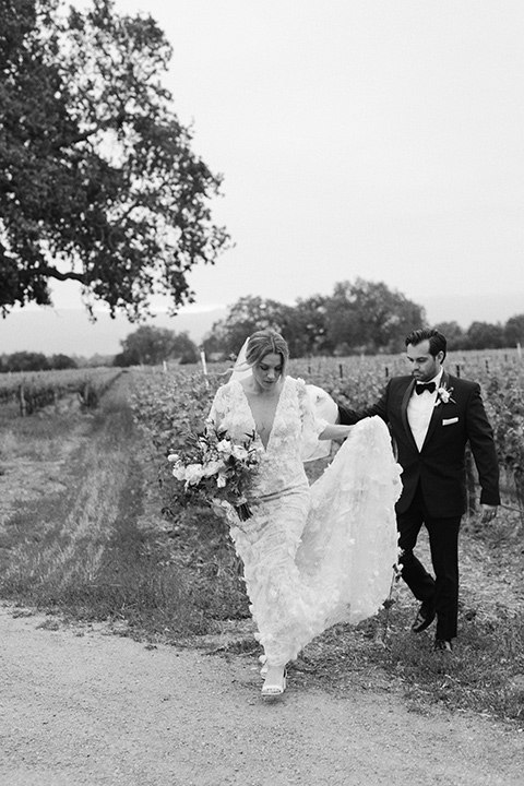  bride in a white gown with floral appliques and trumpet sleeves, the groom in a black tuxedo with black tie accessories 
