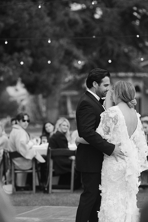  bride in a white gown with floral appliques and trumpet sleeves, the groom in a black tuxedo with black tie accessories