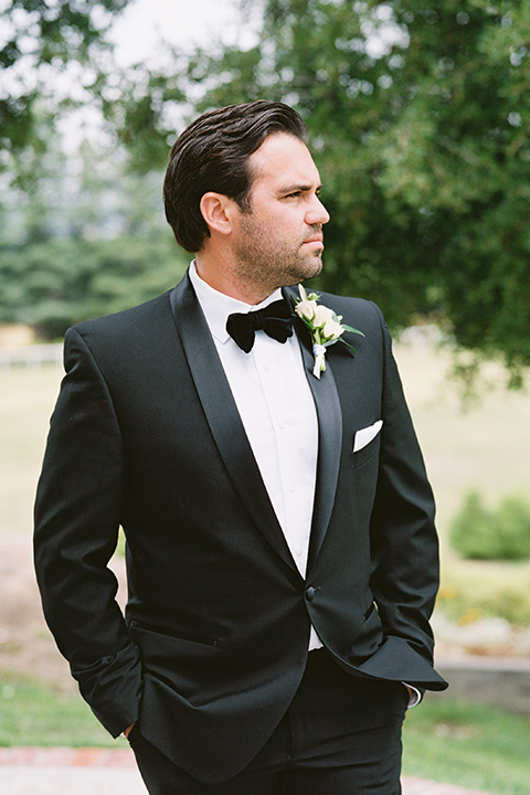  bride in a white gown with floral appliques and trumpet sleeves, the groom in a black tuxedo with black tie accessories