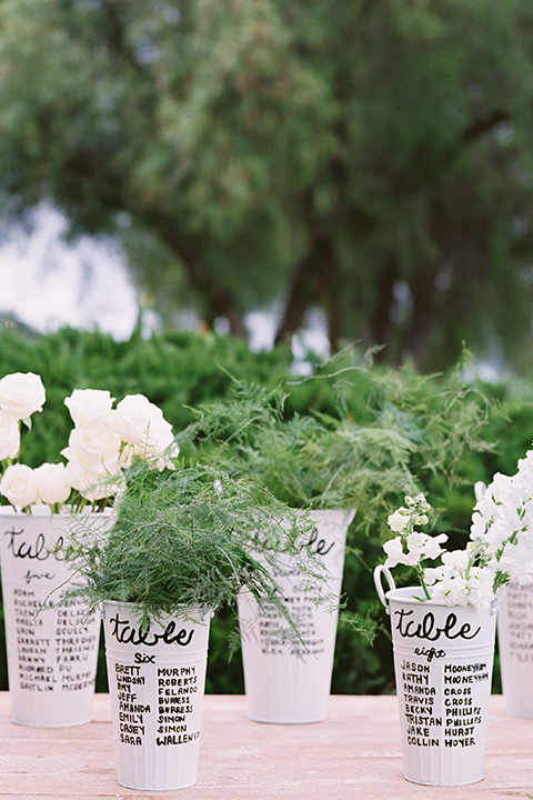  white flower pots with writing for the table numbers 