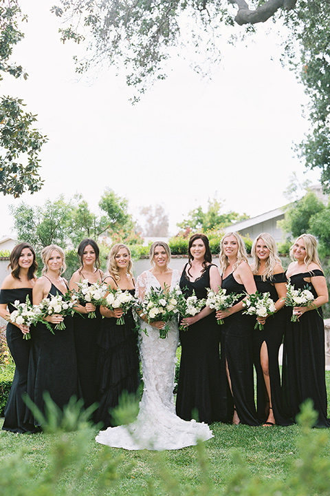  bride in a white gown with floral appliques and trumpet sleeves, the bridesmaids in black dresses in all different styles