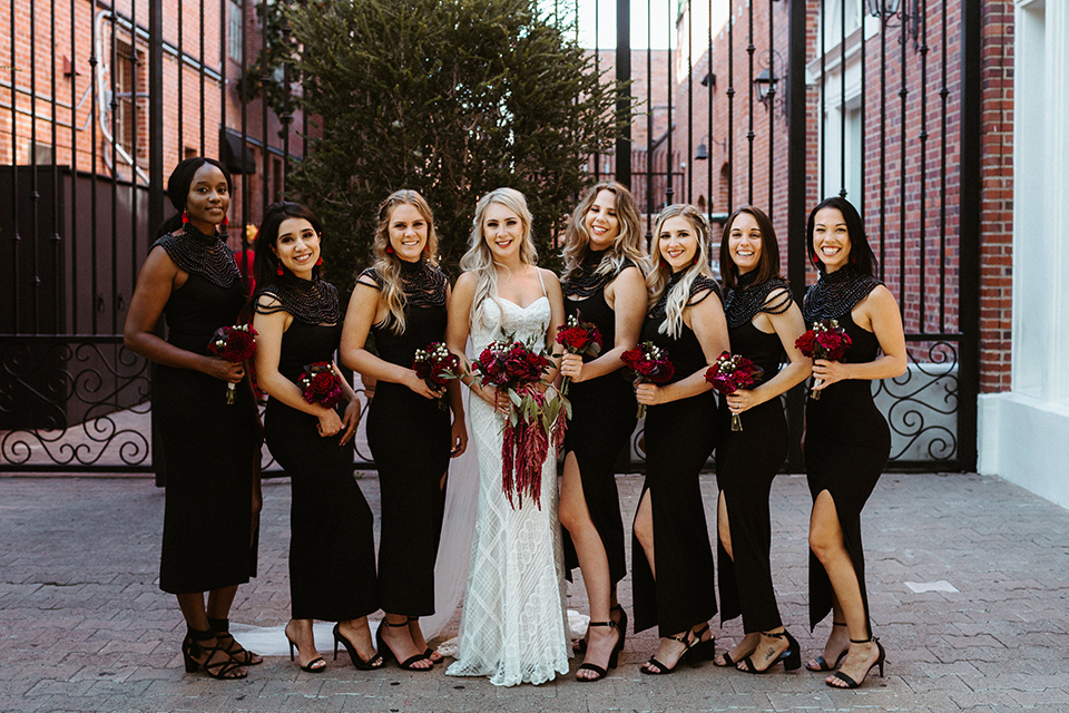  the groom in a burgundy tuxedo with a black bow tie and the groomsmen in burgundy tuxedos