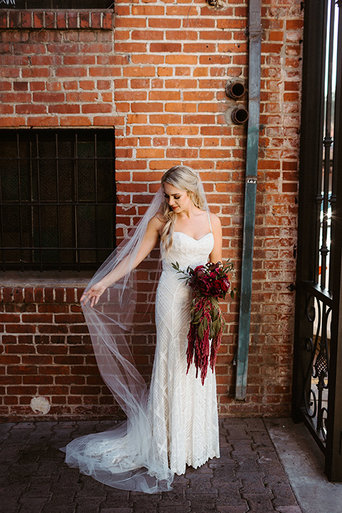 bride in a white formfitting gown with thin lace straps and cathedral veil