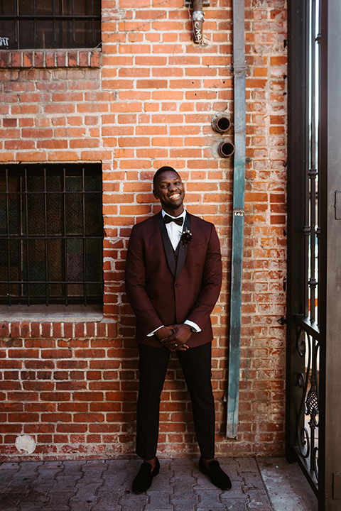 groom in a burgundy tuxedo and black bow tie