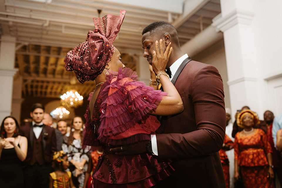 bride in a formfitting lace white gown with thin straps, and the groom in a burgundy tuxedo with a black bow tie.