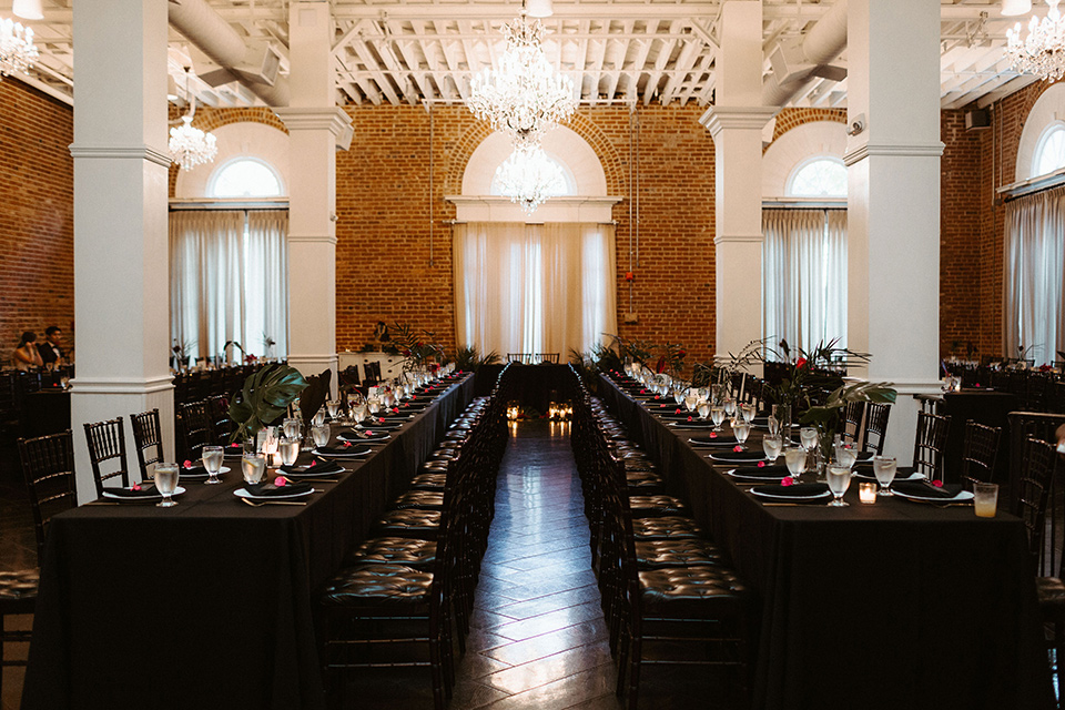  brick style venue with long tables covered in black linens and gold accessories