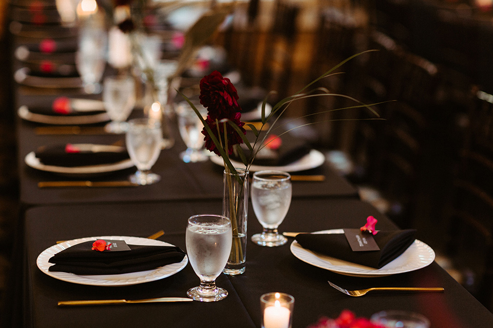  brick style venue with long tables covered in black linens and gold accessories