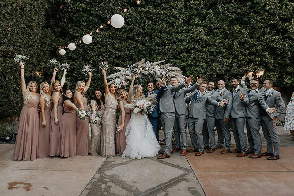 bride in a white ballgown and lace bodice detailing, the groom in a dark blue suit with a pink long tie.  The bridesmaids in pink dresses and groomsmen in light grey suits with dark blue vests