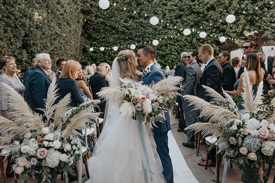 bride in a white ballgown and lace bodice detailing, the groom in a dark blue suit with a pink long tie