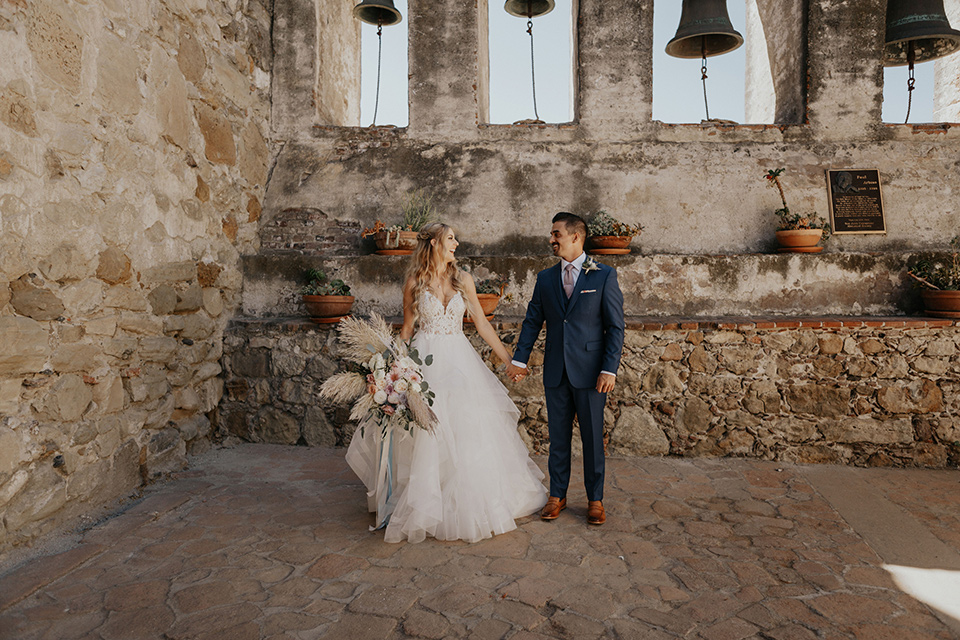 bride in a white ballgown and lace bodice detailing, the groom in a dark blue suit with a pink long tie