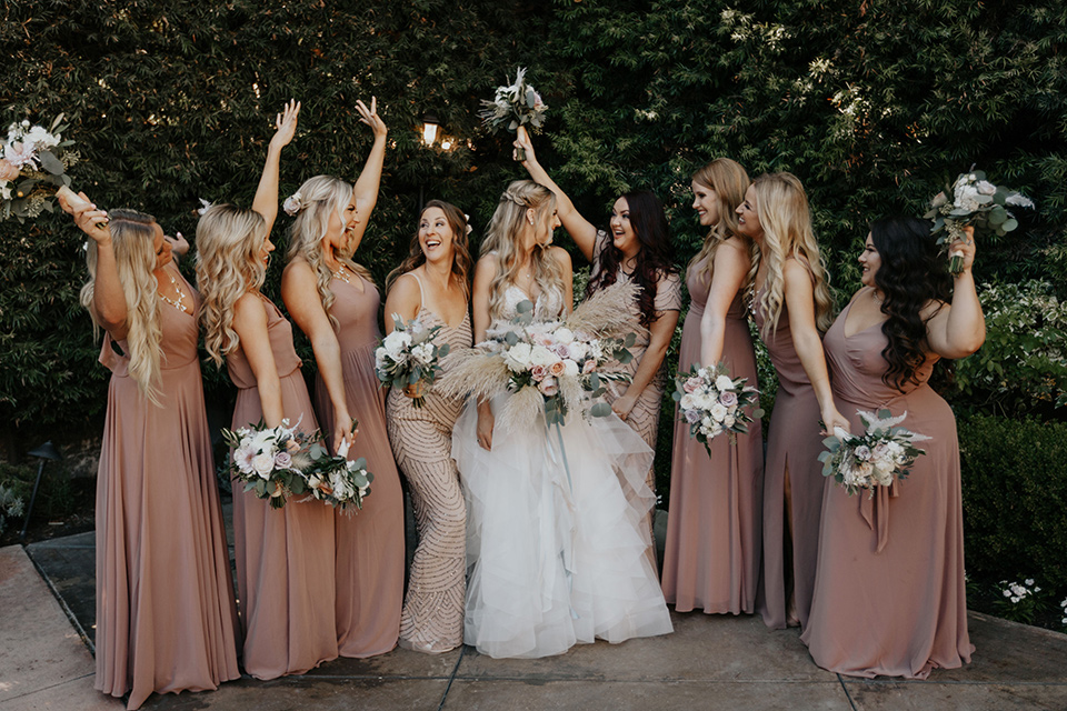 bride in a white ballgown and lace bodice detailing, bridesmaids in light pink and mauve toned gowns